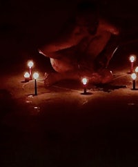 a man kneeling on the ground with candles in his hands